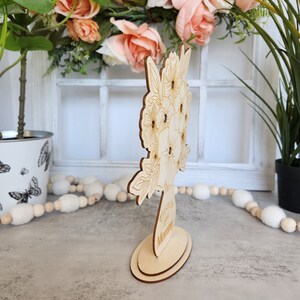 May include: A wooden floral bouquet decoration with an oval base. The bouquet features etched flower and leaf designs. The base has the text "Thinking of Mommy" etched into it. The decoration is made of light-colored wood.