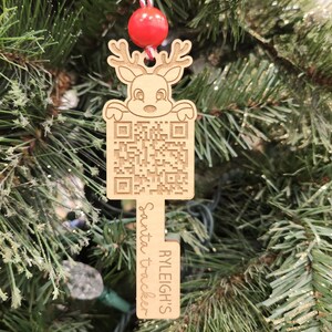 May include: Wooden Christmas ornament shaped like a key with a reindeer peeking over the top. The key has a QR code and the text "RYLEIGH'S Santa tracker" on it.