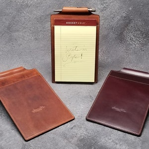 May include: Two leather notepads with a pen holder and a notepad with lined paper. The notepads are brown and burgundy. The text "DOCKETGOLD" is on the notepad.