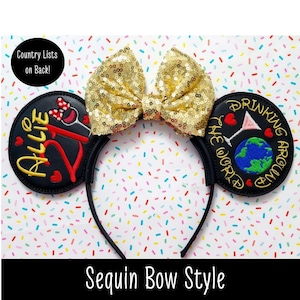May include: A black headband with two circular ears featuring embroidery. The left ear displays the text 'ALLIE 21' with a small bow icon. The right ear shows a globe, a martini glass, and the text 'DRINKING AROUND THE WORLD'. A gold sequin bow sits between the ears.