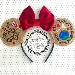 May include: A black headband with cork ears and a large red bow. The left ear has text that says "Meet Me At The Minnie Bar" with a wine glass graphic. The right ear says "Drinking Around The World" with a globe graphic.