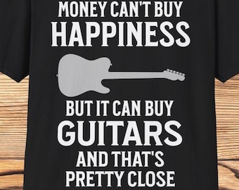 May include: Black t-shirt with white text and a guitar graphic. The text reads: "MONEY CAN'T BUY HAPPINESS BUT IT CAN BUY GUITARS AND THAT'S PRETTY CLOSE."