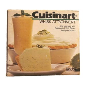 May include: Cuisinart whisk attachment box with a slice of pie, a glass of orange drink, and a pie with whipped cream. The box has the text "Cuisinart WHISK ATTACHMENT" and "For use only with Cuisinart DLC-8 Series food processors".