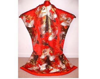 May include: A vibrant red kimono with a detailed pattern of white cranes in flight. The traditional Japanese garment features gold and brown accents, creating a striking contrast. The kimono is displayed open, showcasing its full design.