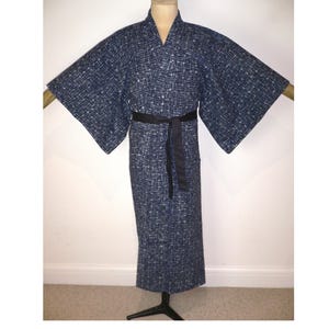May include: A navy blue kimono with a white geometric pattern and wide sleeves. The kimono is tied with a black belt. The garment is displayed on a mannequin. This traditional Japanese garment is suitable for casual wear or special occasions.