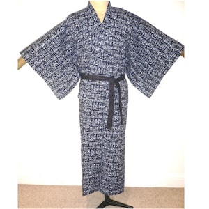 May include: A navy blue and white patterned kimono-style robe with wide sleeves and a black belt. The robe is displayed on a mannequin. The fabric has a textured appearance.