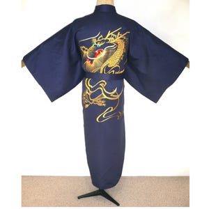 May include: A dark blue kimono featuring a large, detailed gold dragon embroidery on the back. The dragon design includes red and white accents on the face. The garment has wide sleeves, a high collar, and a matching fabric belt at the waist.