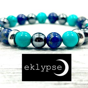 May include: A turquoise, blue, and silver beaded bracelet with a silver charm that says "eklypse" in white lettering.