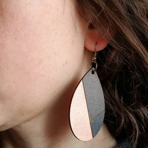 A pair of teardrop-shaped earrings lightweight wood earrings with a geometric block design. The earrings are made of thin wood and have a black, walnut stain and rose gold finish sections.