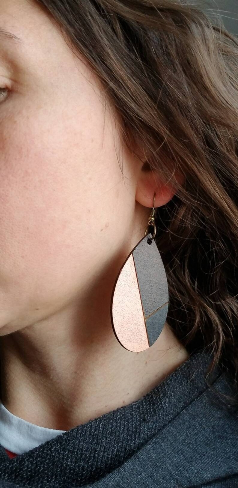 A pair of teardrop-shaped earrings lightweight wood earrings with a geometric block design. The earrings are made of thin wood and have a black, walnut stain and rose gold finish sections.