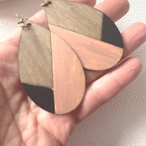 A pair of teardrop-shaped earrings lightweight wood earrings with a geometric block design. The earrings are made of thin wood and have a black, walnut stain and rose gold finish sections.