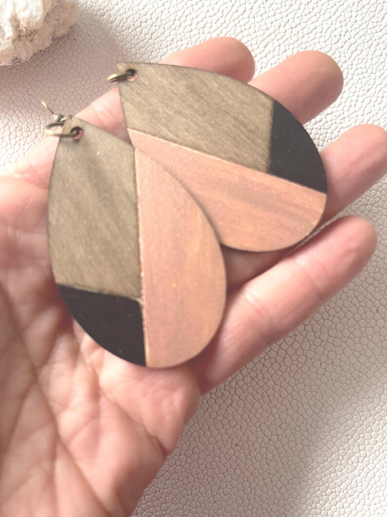 A pair of teardrop-shaped earrings lightweight wood earrings with a geometric block design. The earrings are made of thin wood and have a black, walnut stain and rose gold finish sections.