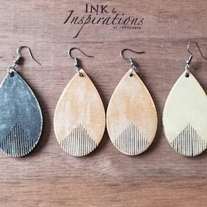 May include: Three pairs of teardrop-shaped wooden earrings with a geometric design. The earrings are in three colors: gray, beige, and cream.