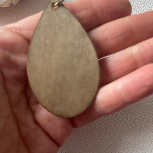 back of A pair of teardrop-shaped earrings lightweight wood earrings with a geometric block design. The earrings are made of thin wood and have a black, walnut stain and rose gold finish sections.