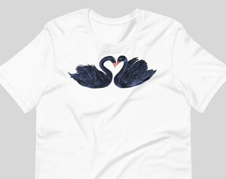 May include: A white t-shirt with a black and white illustration of two black swans with their necks intertwined in a heart shape.