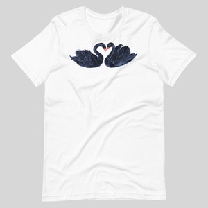 May include: White t-shirt with a graphic of two black swans forming a heart shape with their necks.