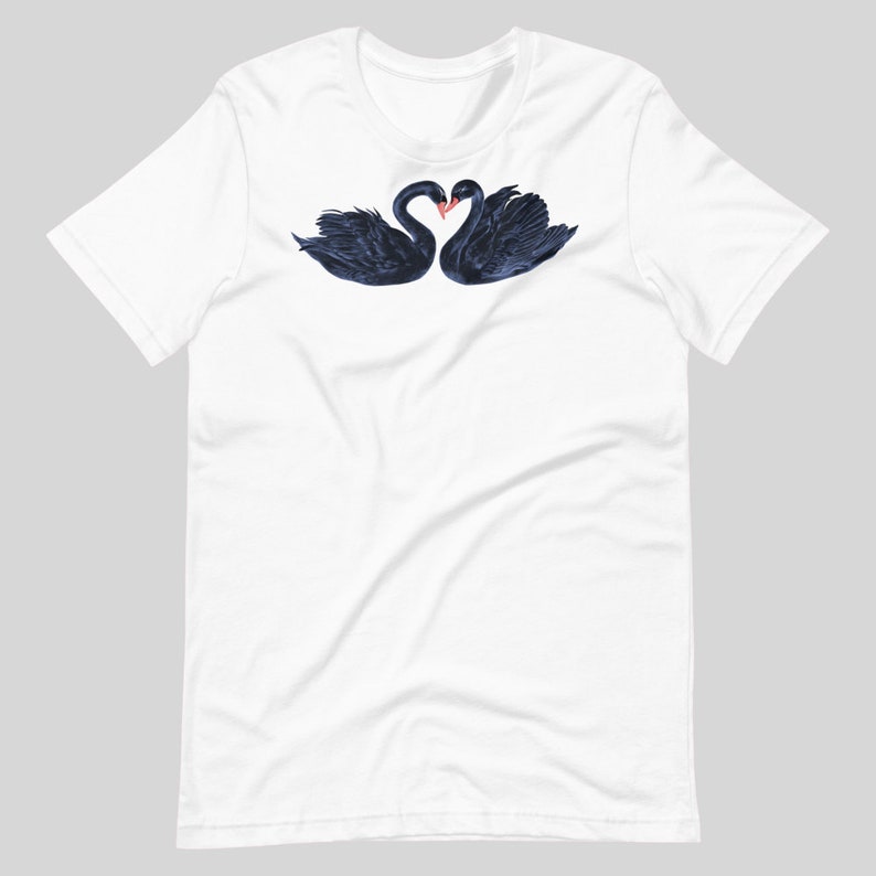 May include: White t-shirt with a graphic of two black swans forming a heart shape with their necks.