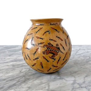 Può includere: Un vaso in ceramica marrone con forma arrotondata e un disegno di formiche e una lucertola. Il vaso è decorato con vernice nera e rossa.