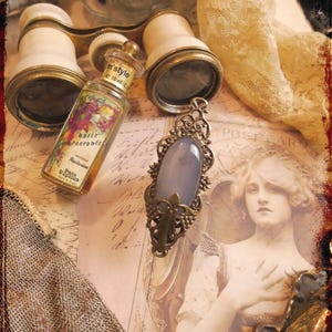 May include: A vintage still life arrangement with an opera glass, a perfume bottle, and a pendant with a blue stone. The scene includes a lace scarf and a vintage illustration, evoking a romantic, old-world atmosphere. The perfume bottle is 10 ml.