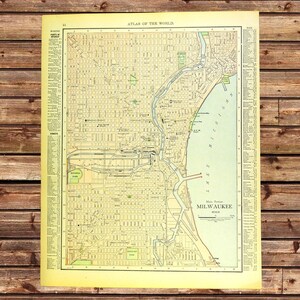 May include: Vintage map of Milwaukee, Wisconsin, from the Atlas of the World. The map features a detailed street grid, parks, and the shoreline of Lake Michigan. The map is printed on aged paper with a sepia tone.