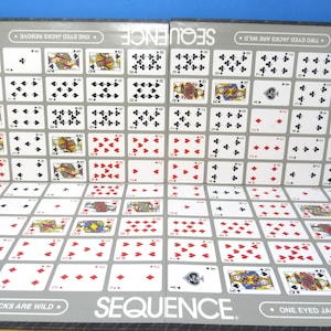 May include: A Sequence board game featuring a grid of playing cards with red and black suits. The board includes text stating "SEQUENCE" and "TWO EYED JACKS ARE WILD" and "ONE EYED JACKS REMOVE" printed in white on a gray background border.