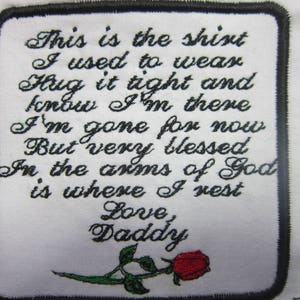 May include: White embroidered patch with black stitching and a black border. The patch features a poem about a loved one who has passed away. The poem reads: "This is the shirt I used to wear Hug it tight and know I'm there I'm gone for now But very blessed In the arms of God is where I rest Love, Daddy". A red rose with green leaves is embroidered at the bottom of the patch.