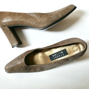 May include: A pair of brown snakeskin pumps with a high block heel. The shoes are by Stuart Weitzman.