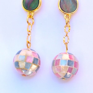 May include: A pair of gold tone earrings with a teardrop shaped iridescent shell stone and a round, multi-colored shell bead.