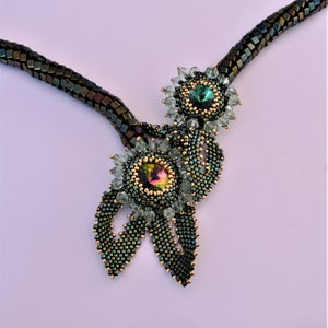 May include: A green and gold beaded necklace with two flower-shaped pendants featuring iridescent gemstones.