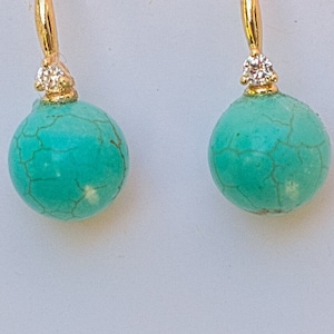 May include: A pair of turquoise and gold earrings with a small diamond accent on each earring.