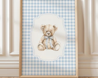 May include: A framed print with a blue and white gingham pattern. A white oval frame with a brown teddy bear wearing a blue bow is centered on the print.