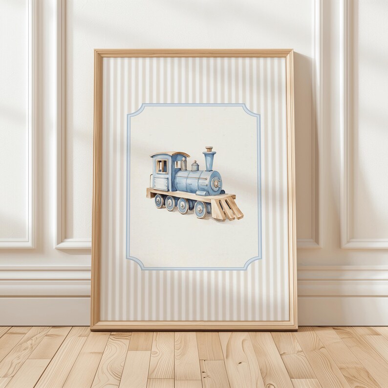 May include: A framed watercolor illustration of a blue toy train with a white background. The train has a black chimney and wheels. The frame has a light brown wood finish and a white and light blue striped background.