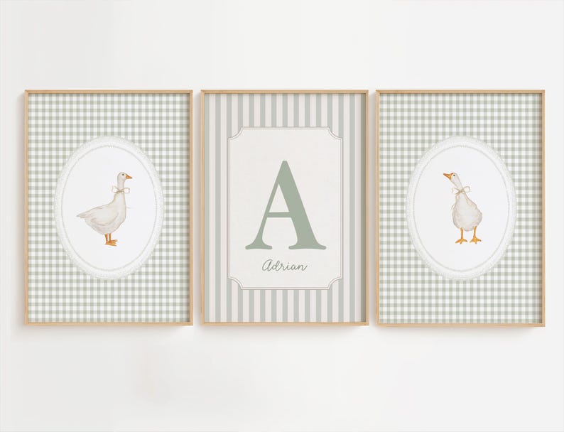 May include: Three framed wall art prints with light wooden frames. The two outer prints feature a white goose in an oval frame against a sage green gingham background. The center print displays a large letter A and the name Adrian in script.