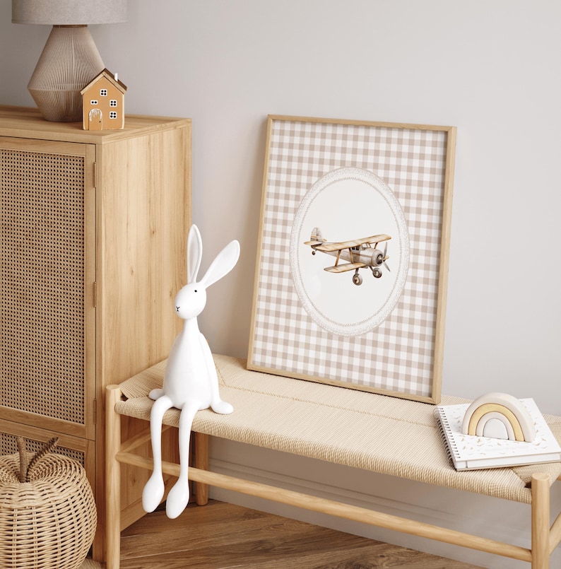 Pu&ograve; includere: Una stampa incorniciata con un'illustrazione ad acquerello di un biplano vintage. L'opera d'arte &egrave; ambientata su un motivo a quadretti beige e bianco, incorniciata in legno chiaro. La scena include una statuina di coniglio bianco e una panca di legno.