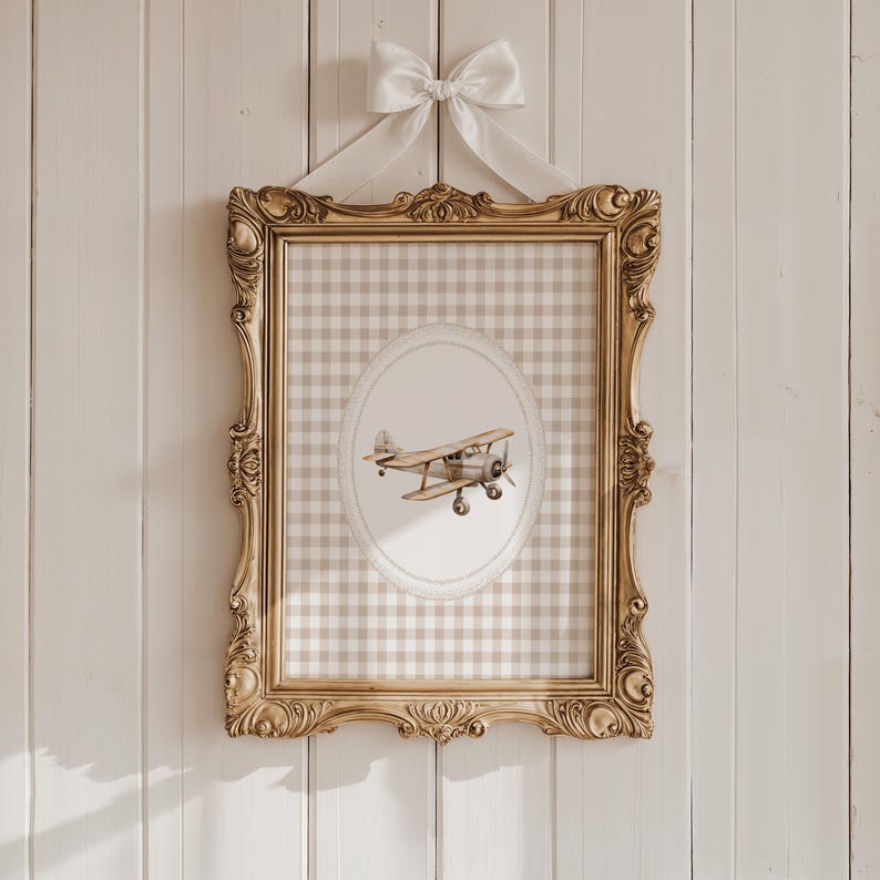 Pu&ograve; includere: Un'opera d'arte incorniciata con un'illustrazione di aereo vintage. La cornice dorata e ornata circonda uno sfondo a quadretti gingham. Un fiocco bianco &egrave; legato in alto. L'opera &egrave; pensata per l'arredamento della cameretta.