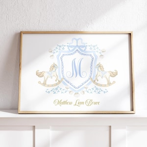 Könnte beinhalten: Gerahmter Druck mit hellblauem Wappen und dem Buchstaben "M", flankiert von zwei Schaukelpferd-Illustrationen. Der Name "Matthew Liam Bruce" steht in goldener Schrift darunter. Der Rahmen ist aus hellem Holz.