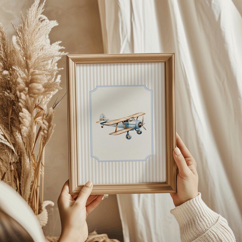 May include: A framed print of a blue and brown vintage airplane with a light blue background and white stripes. The frame is made of wood and has a light brown finish.
