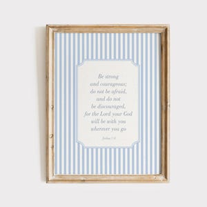 Könnte beinhalten: Ein gerahmter Druck mit hellblauem und weiß gestreiftem Hintergrund. Der Druck zeigt ein zentrales weißes Feld mit Text in einer weichen, eleganten Schriftart. Der Text lautet: "Sei stark und mutig; fürchte dich nicht..." Josua 1:9.