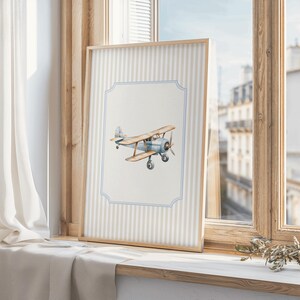 May include: A framed print of a blue and white watercolor illustration of a vintage airplane on a striped background.