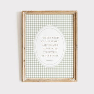 Pode incluir: Impressão emoldurada com um fundo de padrão xadrez vichy verde claro e branco. A impressão apresenta um design oval com o texto "FOR THIS CHILD WE HAVE PRAYED, AND THE LORD HAS GRANTED THE DESIRES OF OUR HEARTS." A moldura é castanho claro.