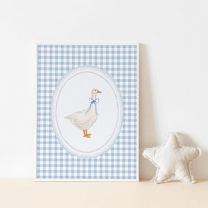 May include: A framed print of a white goose with a blue bow on a blue and white gingham background.
