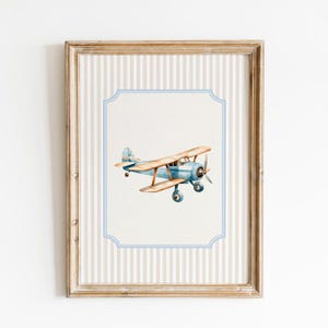 May include: A framed print of a vintage blue and brown airplane with a light blue border and a striped background.