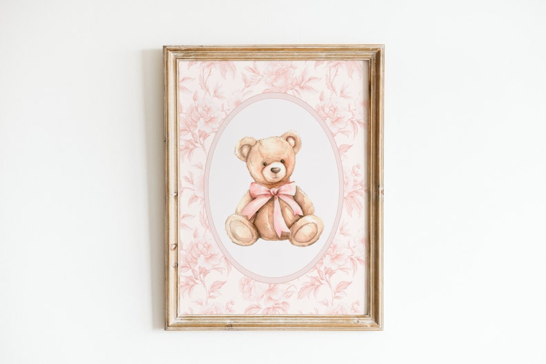 Pu&ograve; includere: Una stampa incorniciata di un'illustrazione ad acquerello di un orsacchiotto con un fiocco rosa, su uno sfondo floreale rosa.
