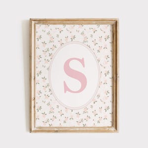 Peut inclure: Tableau encadré avec un fond à motifs floraux et un ovale central. Une lettre "S" rose est à l'intérieur de l'ovale. Le cadre est de couleur marron clair. Idéal pour une chambre d'enfant.