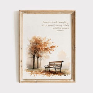 Op de afbeelding: Ingelijste aquarelprint met een parkbank onder bomen met herfstbladeren. De tekst luidt: "Er is een tijd voor alles, en een seizoen voor elke activiteit onder de hemel." Prediker 3.