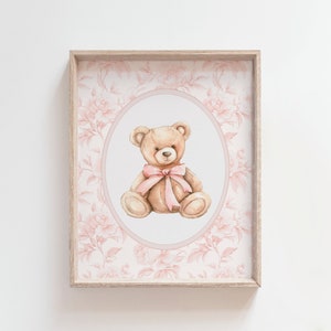 Pu&ograve; includere: Una stampa incorniciata con un'illustrazione ad acquerello di un orsacchiotto marrone con un fiocco rosa, su uno sfondo floreale rosa.