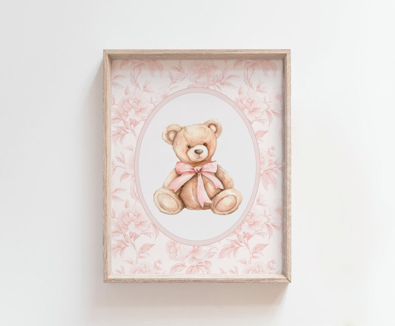 Pu&ograve; includere: Una stampa incorniciata con un'illustrazione ad acquerello di un orsacchiotto marrone con un fiocco rosa, su uno sfondo floreale rosa.