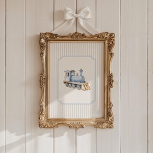 May include: A framed print of a blue toy train with gold wheels and a white background. The frame is gold with ornate details and is hanging on a white wood wall.