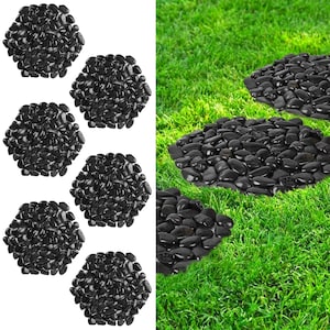 May include: Black pebble stepping stones arranged in a path on a green lawn. The stones are round and smooth, and they are arranged in a straight line.