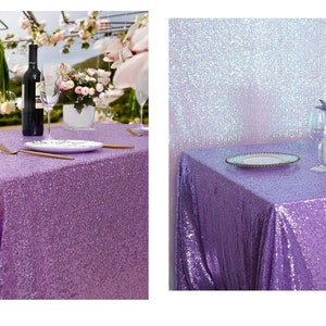 May include: A lavender sequin tablecloth with a wine bottle, glasses, and plates set on top. The tablecloth is shown in two different settings, one with a floral backdrop and the other with a sparkly backdrop.